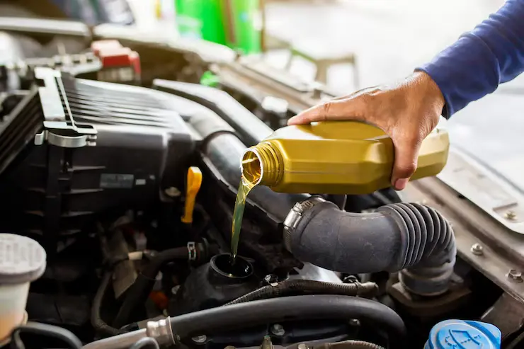 bilmekaniker erstatter å helle fersk olje inn i motoren